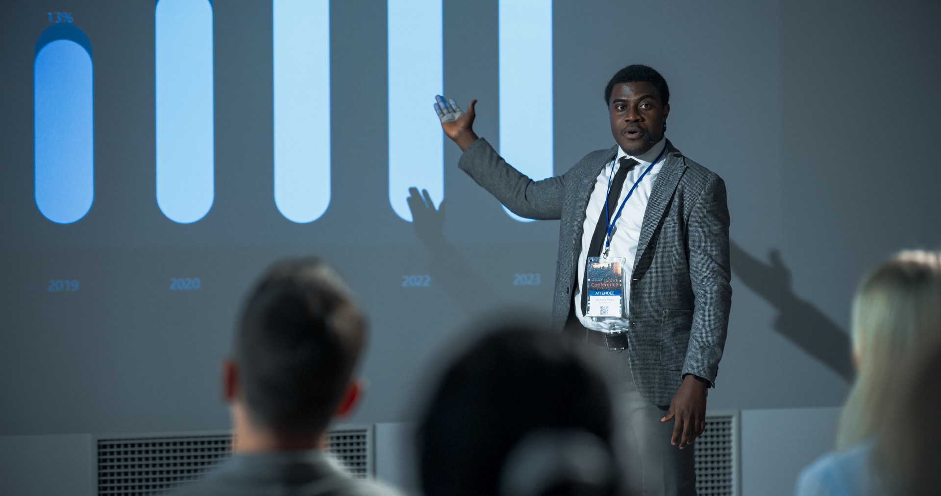 Successful Black Businessman Giving Presentation At International Business Conference. African American Male Entrepreneur Pitching An Innovative Startup Idea To Diverse Audience Of Investors.